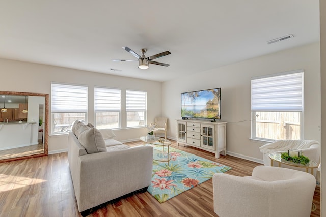 living room featuring baseboards, visible vents, and wood finished floors