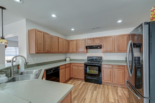 kitchen with visible vents, under cabinet range hood, light wood-type flooring, black appliances, and a sink