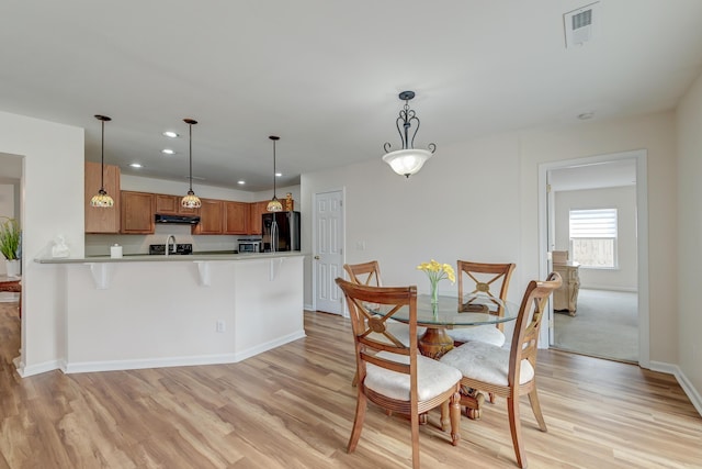 dining room featuring baseboards, light wood-style flooring, visible vents, and recessed lighting