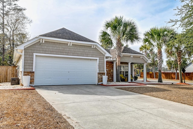 view of front of home with an attached garage, a shingled roof, fence, stone siding, and driveway