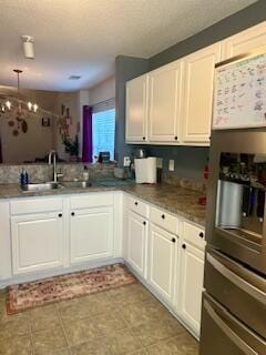 kitchen with pendant lighting, sink, an inviting chandelier, white cabinetry, and stainless steel fridge with ice dispenser