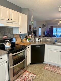 kitchen with black dishwasher, sink, white cabinets, and range with two ovens