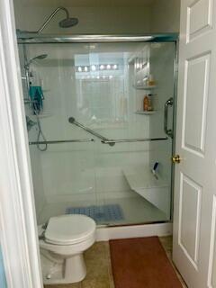 bathroom featuring walk in shower, tile patterned flooring, and toilet