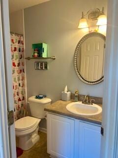 bathroom featuring toilet, vanity, and curtained shower