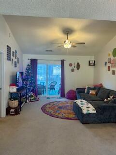 living room featuring ceiling fan, carpet flooring, and lofted ceiling