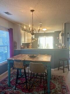 interior space with decorative light fixtures, a notable chandelier, a textured ceiling, white cabinets, and stainless steel fridge