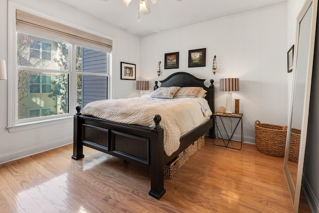 bedroom with baseboards, light wood-style floors, and a ceiling fan