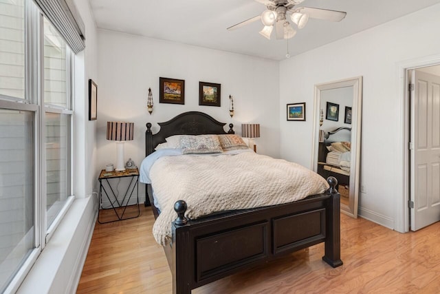 bedroom featuring a ceiling fan, light wood-style floors, and baseboards