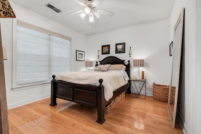 bedroom with ceiling fan, visible vents, baseboards, and light wood-style flooring