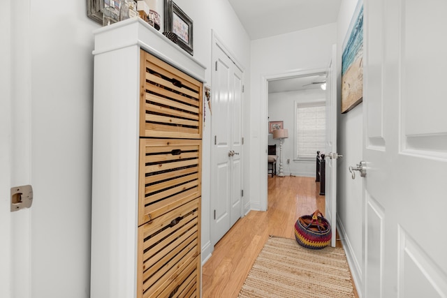 corridor with a sauna, baseboards, and light wood-style flooring