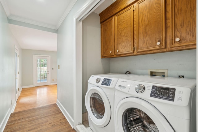 clothes washing area with cabinet space, baseboards, ornamental molding, washing machine and clothes dryer, and light wood-style floors