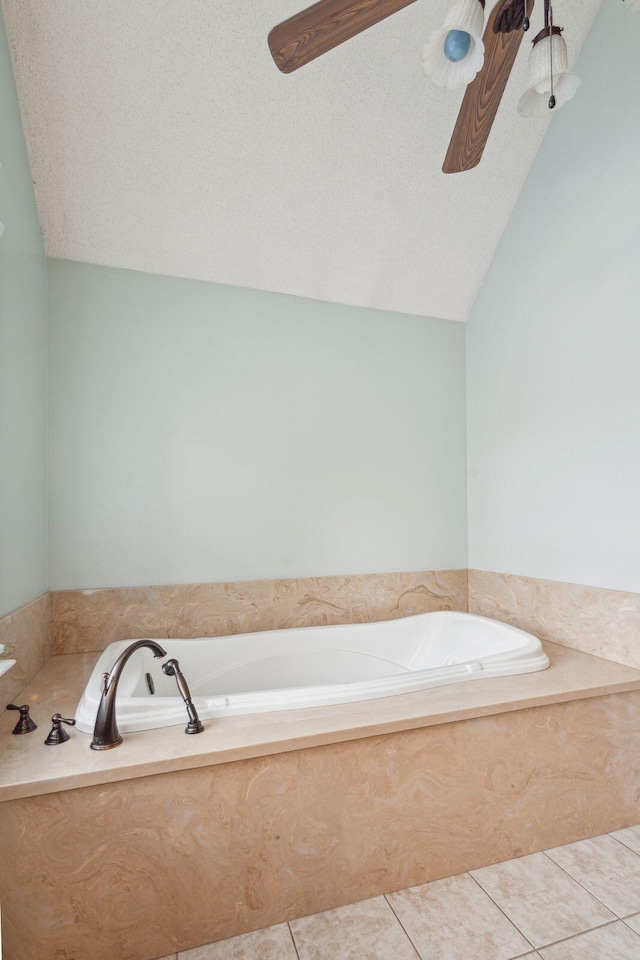 bathroom with lofted ceiling, a textured ceiling, a garden tub, a ceiling fan, and tile patterned floors