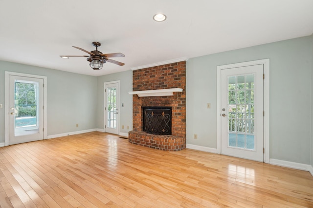 unfurnished living room featuring a brick fireplace, light wood-style flooring, and a healthy amount of sunlight