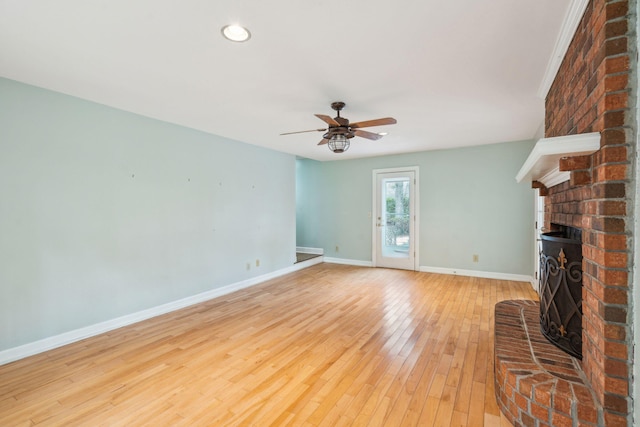 unfurnished living room with light wood finished floors, baseboards, ceiling fan, a fireplace, and recessed lighting