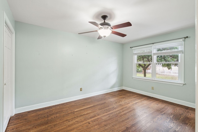 spare room with dark wood-type flooring, visible vents, baseboards, and a ceiling fan