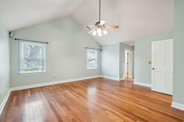 spare room featuring ceiling fan, a textured ceiling, baseboards, vaulted ceiling, and light wood-type flooring