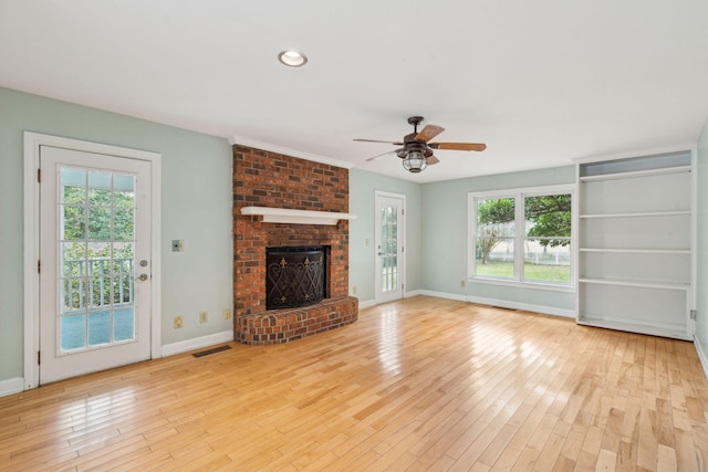 unfurnished living room with a healthy amount of sunlight, a fireplace, visible vents, and wood finished floors