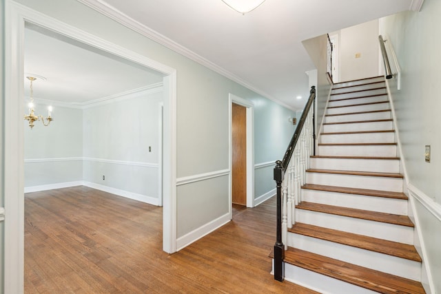 stairs with a chandelier, baseboards, wood finished floors, and crown molding