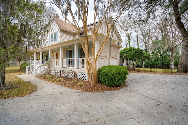 view of side of property with an attached garage, covered porch, and fence