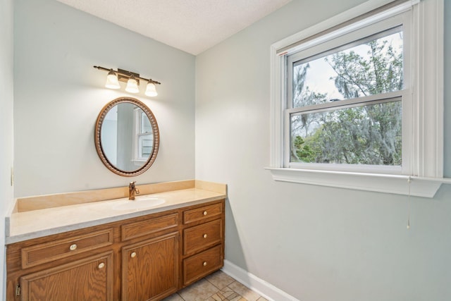 bathroom with baseboards, plenty of natural light, a textured ceiling, and vanity