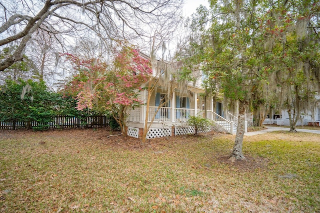 view of property exterior featuring fence, a porch, and a lawn