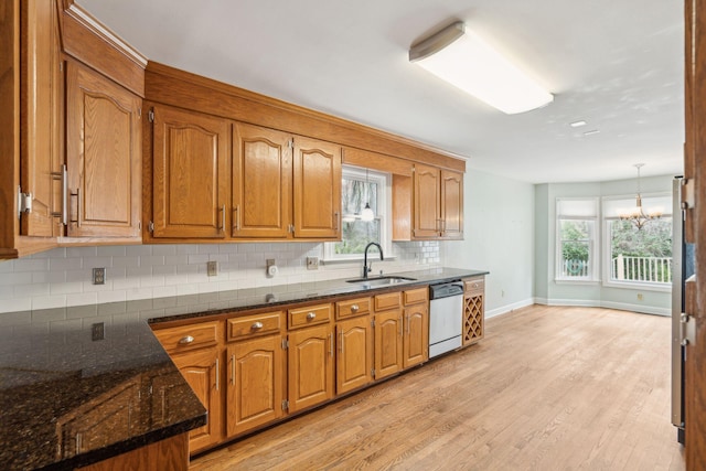 kitchen with brown cabinets, stainless steel dishwasher, light wood-style floors, and a sink