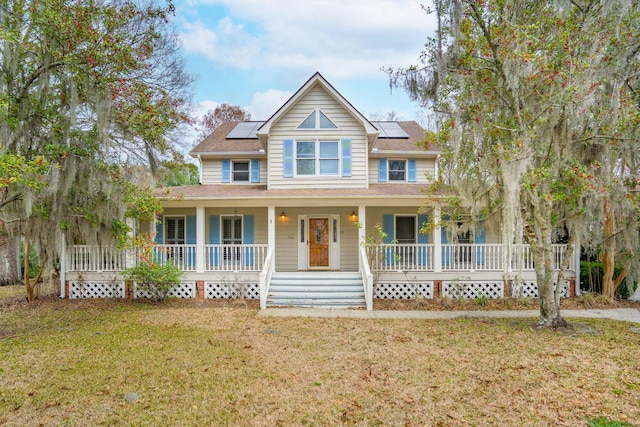 farmhouse-style home featuring a porch, a front yard, and roof mounted solar panels