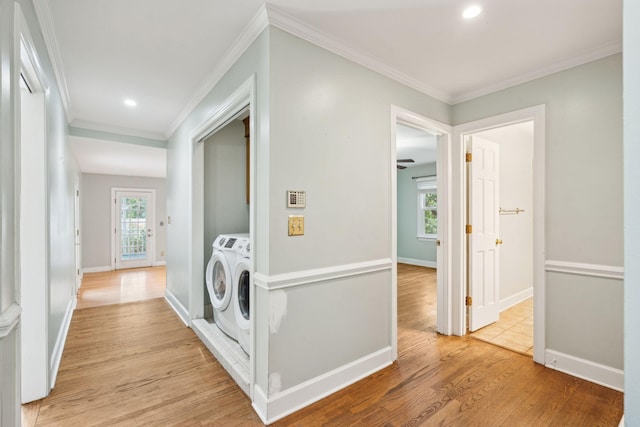 hallway featuring light wood-style flooring, ornamental molding, baseboards, and washing machine and clothes dryer