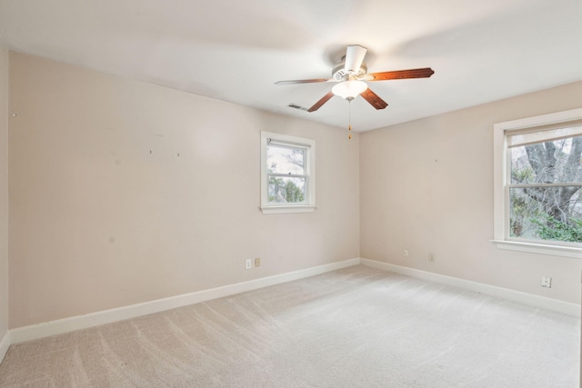 spare room with a ceiling fan, visible vents, light carpet, and baseboards