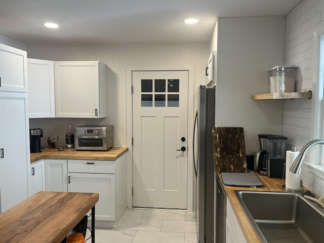 1866 Ashley Hall Rd, Charleston, SC 29407 - kitchen featuring butcher block countertops, a sink, light marble finish flooring, white cabinetry, and freestanding refrigerator