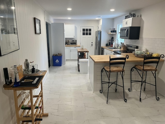 1866 Ashley Hall Rd, Charleston, SC 29407 - kitchen with butcher block countertops, stainless steel appliances, a sink, light marble finish floors, and a peninsula