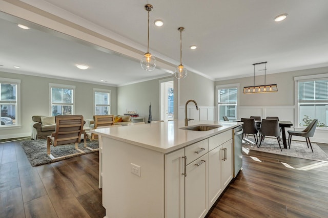 kitchen featuring dishwasher, crown molding, dark wood-style flooring, and a sink