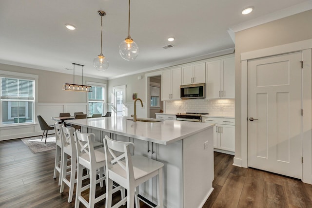 kitchen featuring a sink, visible vents, ornamental molding, range, and stainless steel microwave