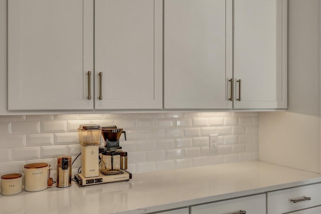 details featuring white cabinets, light stone counters, and decorative backsplash