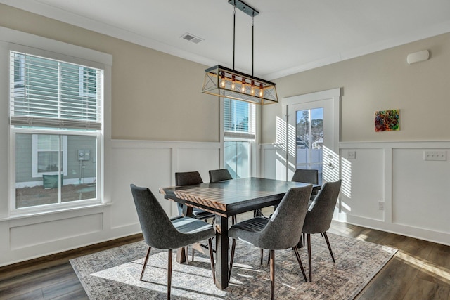 dining room featuring a decorative wall, a wainscoted wall, visible vents, dark wood finished floors, and crown molding