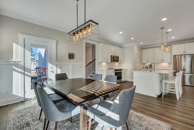 dining area with a wainscoted wall, crown molding, dark wood finished floors, recessed lighting, and stairway