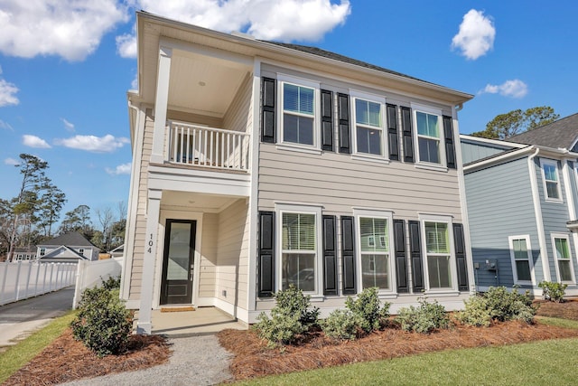 view of front of house featuring a balcony and fence