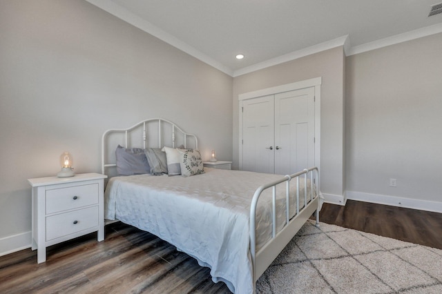 bedroom with wood finished floors, visible vents, baseboards, a closet, and crown molding