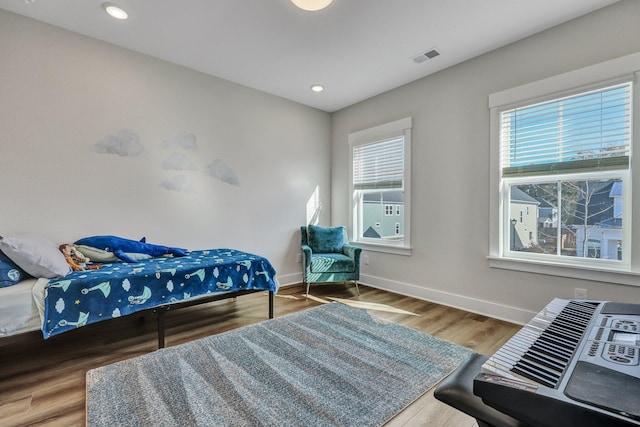 bedroom featuring multiple windows, wood finished floors, visible vents, and baseboards