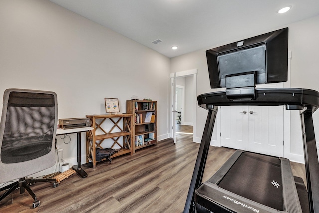 exercise area featuring baseboards, wood finished floors, visible vents, and recessed lighting