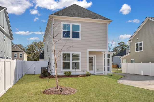 back of house with a patio area, a fenced backyard, a yard, and roof with shingles