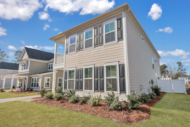 exterior space featuring a lawn, fence, and a balcony