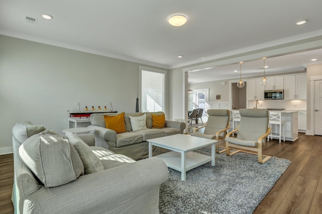 living room featuring dark wood-type flooring, recessed lighting, visible vents, and crown molding