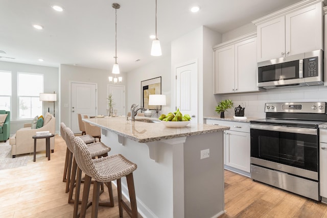 125 Brown Swiss Cir, Summerville, SC 29483 - kitchen featuring a breakfast bar, a sink, decorative backsplash, stainless steel appliances, and light wood-type flooring