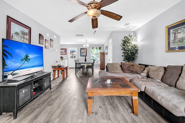 living room with light wood-style floors, visible vents, and a ceiling fan