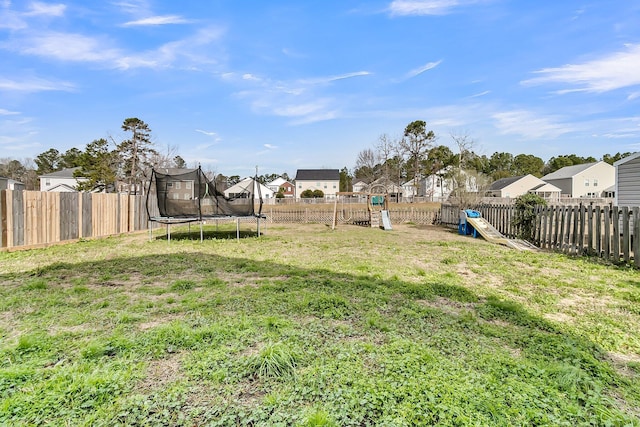 view of yard featuring a fenced backyard, a playground, a residential view, and a trampoline