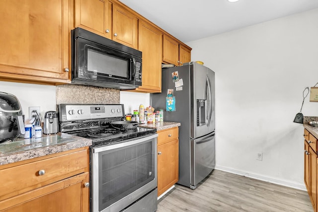 kitchen featuring light wood-style floors, baseboards, decorative backsplash, brown cabinetry, and appliances with stainless steel finishes