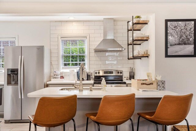 kitchen featuring wall chimney exhaust hood, light wood-type flooring, gray cabinetry, sink, and stainless steel appliances