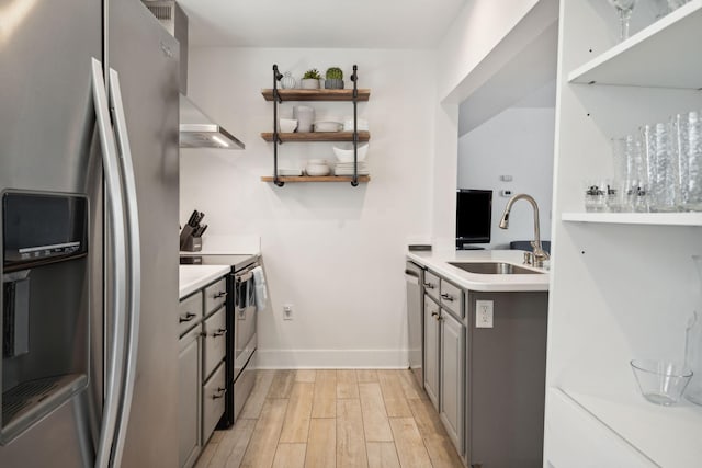 167 Coming St, Charleston, SC 29403 - kitchen featuring appliances with stainless steel finishes, a sink, gray cabinetry, light wood-type flooring, and range hood
