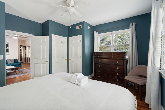 bedroom featuring dark hardwood / wood-style floors, ornamental molding, multiple windows, and ceiling fan